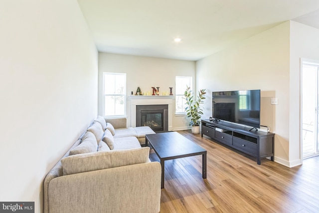 living area with light wood-style floors, recessed lighting, baseboards, and a glass covered fireplace