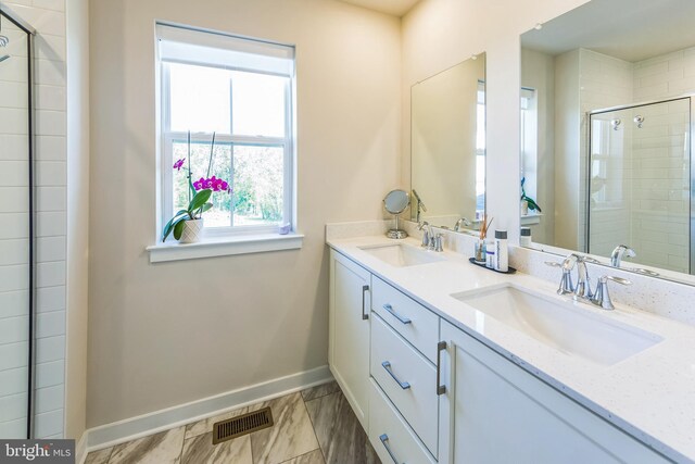 bathroom featuring a sink, baseboards, tiled shower, and visible vents