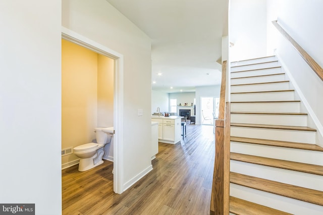 stairs featuring baseboards, visible vents, wood finished floors, and a fireplace