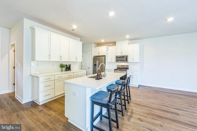 kitchen featuring a sink, appliances with stainless steel finishes, tasteful backsplash, and light wood finished floors