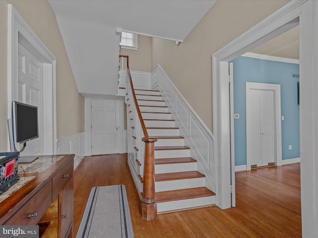 203 S George St, Charles Town, WV 25414 - staircase with wood finished floors, a wainscoted wall, crown molding, and a decorative wall