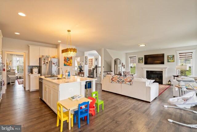 35898 Quantum Pl, Round Hill, VA 20141 - kitchen featuring stainless steel appliances, open floor plan, a sink, a glass covered fireplace, and white cabinetry