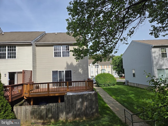 back of property featuring fence, a yard, and a wooden deck