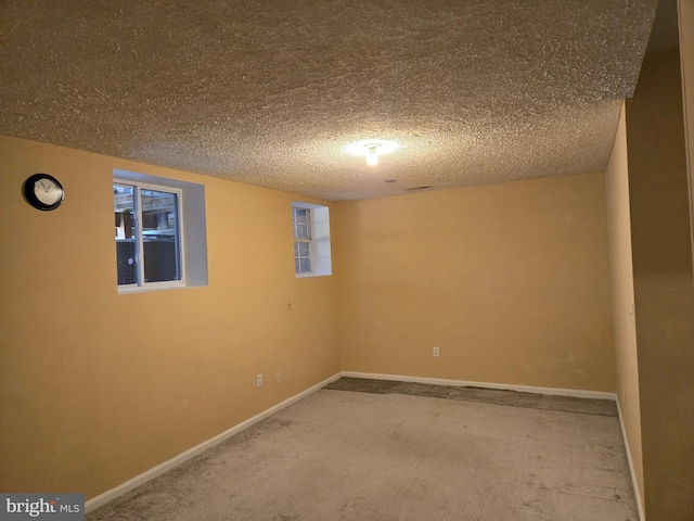 below grade area featuring a textured ceiling, carpet flooring, and baseboards