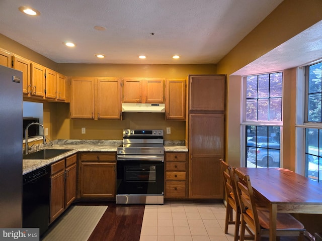 kitchen featuring recessed lighting, light stone counters, stainless steel appliances, under cabinet range hood, and a sink