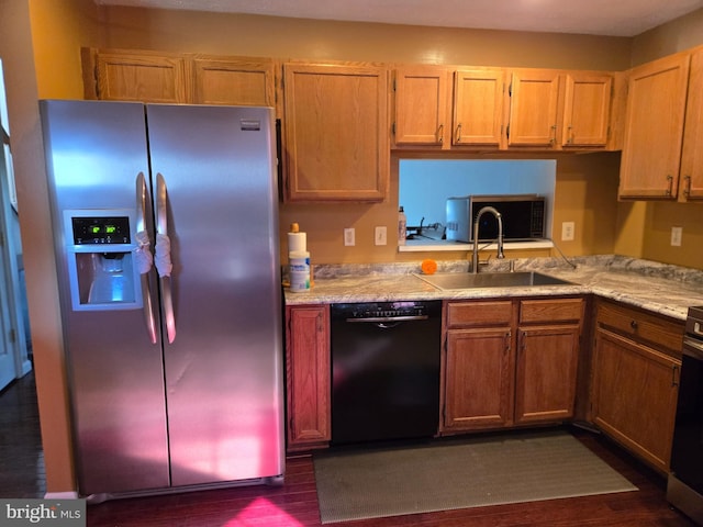 kitchen with dark wood finished floors, stainless steel fridge, black dishwasher, light countertops, and a sink