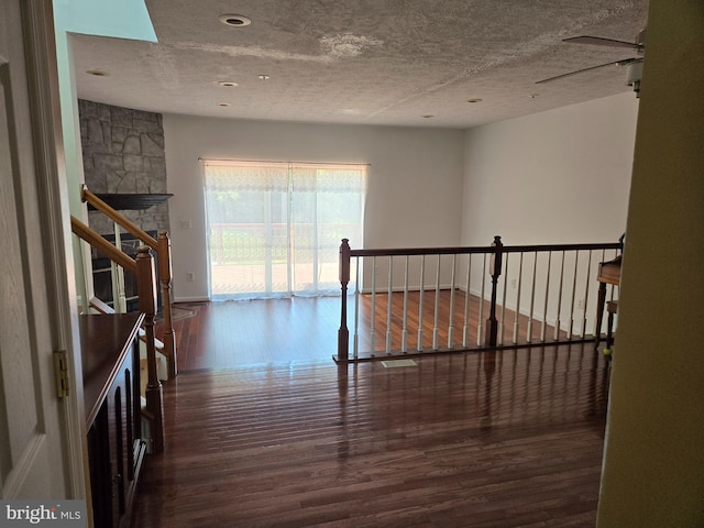 interior space featuring wood finished floors, a stone fireplace, baseboards, visible vents, and a textured ceiling