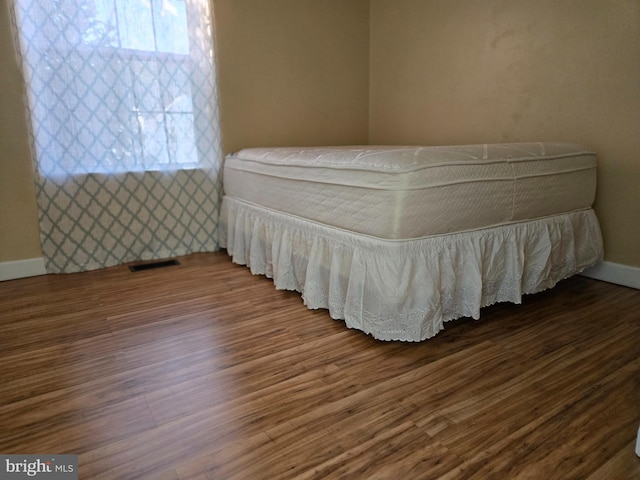 bedroom with visible vents, wood finished floors, and baseboards