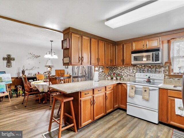 kitchen featuring white electric range, a peninsula, light wood-style floors, and stainless steel microwave