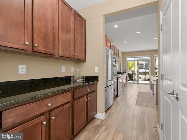 kitchen featuring light wood-type flooring, recessed lighting, brown cabinets, dark stone countertops, and premium appliances