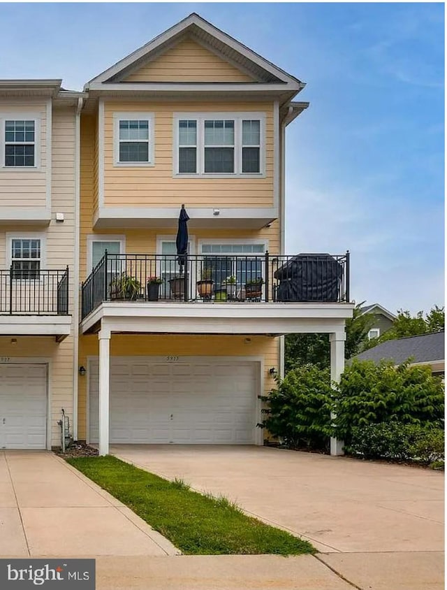 multi unit property with a garage, a balcony, and concrete driveway