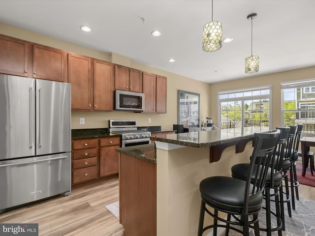 kitchen featuring a kitchen bar, light wood-type flooring, recessed lighting, brown cabinets, and stainless steel appliances