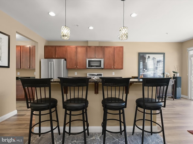 kitchen featuring stainless steel appliances, baseboards, pendant lighting, and light wood-style floors
