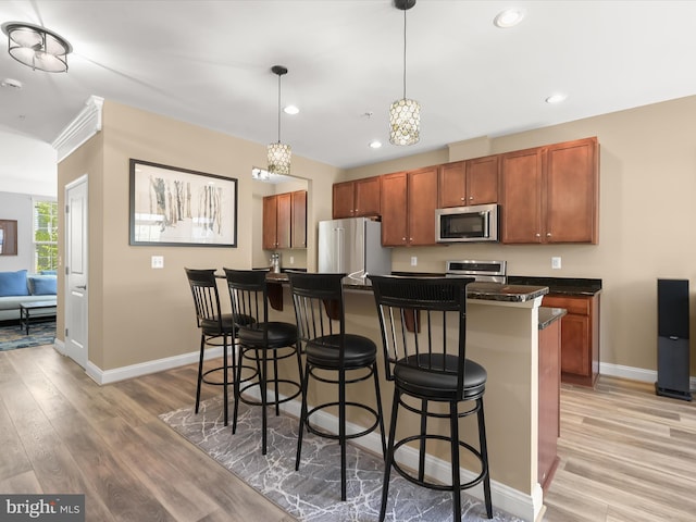 kitchen featuring stainless steel appliances, baseboards, dark countertops, and light wood finished floors