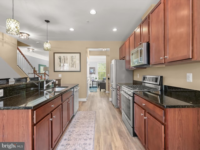 kitchen with light wood-style floors, recessed lighting, a sink, hanging light fixtures, and stainless steel appliances