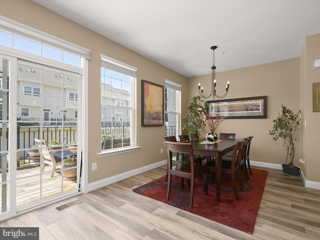 dining room featuring baseboards, a chandelier, wood finished floors, and visible vents