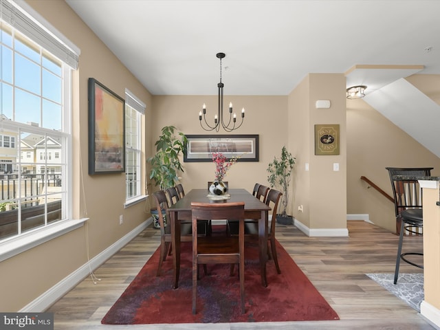 dining space with an inviting chandelier, light wood finished floors, and baseboards
