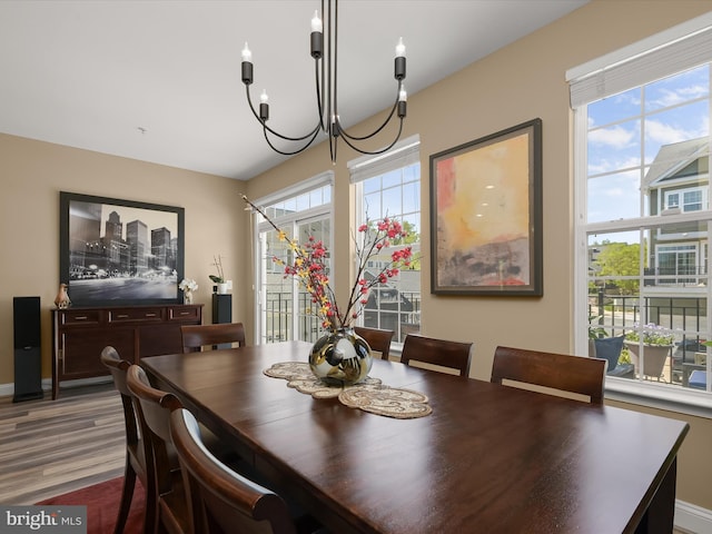 dining room with baseboards, a notable chandelier, plenty of natural light, and wood finished floors