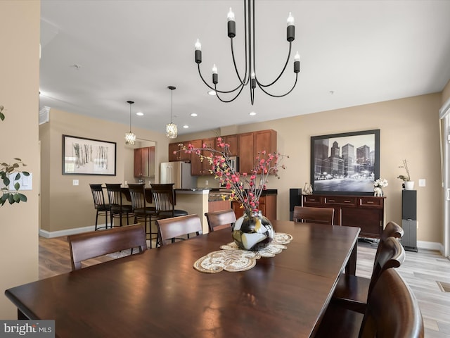 dining space with recessed lighting, light wood finished floors, baseboards, and a notable chandelier