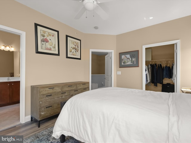 bedroom featuring a closet, wood finished floors, ensuite bathroom, a walk in closet, and a sink