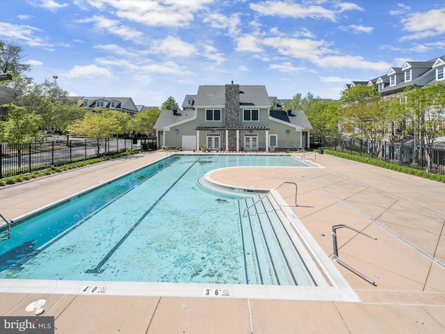 pool with a patio, fence, and a residential view