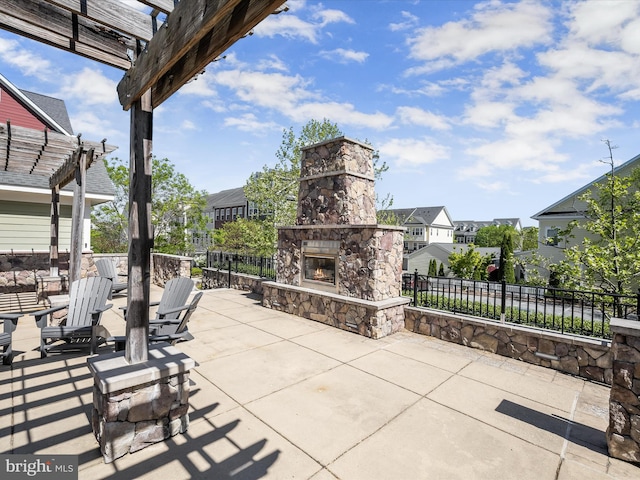 view of patio with an outdoor stone fireplace, fence, a residential view, and a pergola