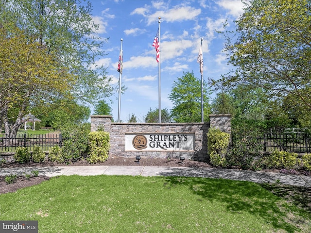 community sign with fence and a lawn