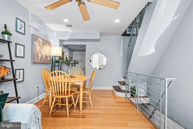 dining area featuring stairs, light wood-style floors, baseboards, visible vents, and a ceiling fan