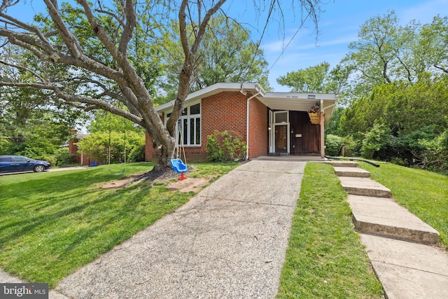 mid-century inspired home featuring brick siding, driveway, a front yard, and an attached carport
