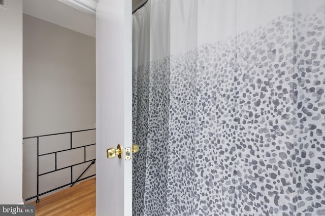 bathroom with wood finished floors and curtained shower