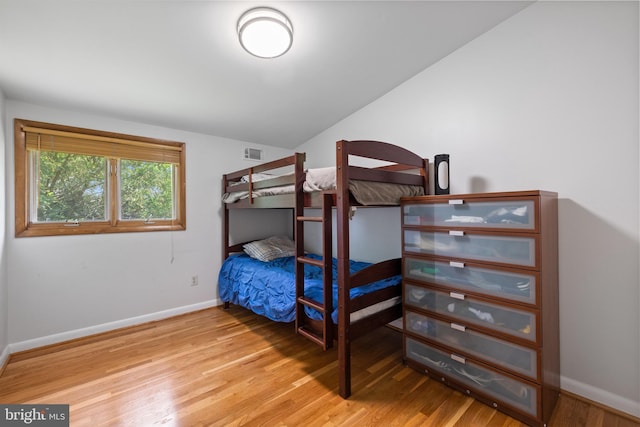 bedroom with wood finished floors, baseboards, and lofted ceiling