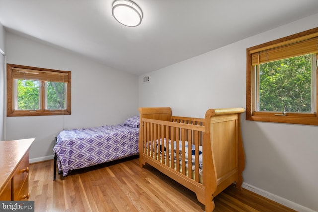 bedroom featuring wood finished floors, vaulted ceiling, and baseboards