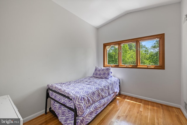 bedroom featuring baseboards, lofted ceiling, and wood finished floors