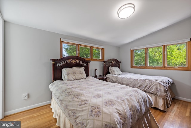bedroom featuring vaulted ceiling, baseboards, and light wood-type flooring