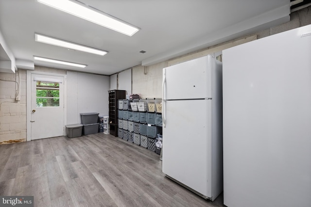 below grade area with freestanding refrigerator and wood finished floors