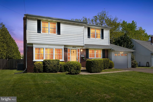 view of front of home featuring a lawn, a garage, brick siding, fence, and aphalt driveway