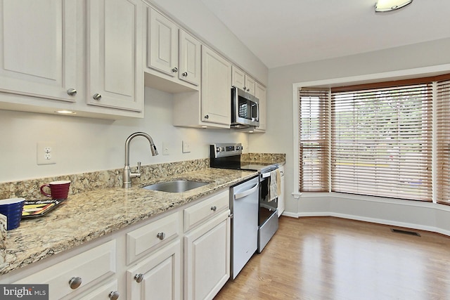 kitchen featuring stainless steel microwave, dishwasher, electric range, a sink, and baseboards