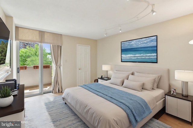 bedroom with access to outside, light wood-style flooring, and track lighting
