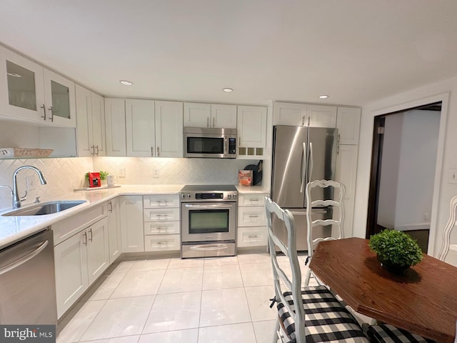 kitchen with appliances with stainless steel finishes, white cabinetry, a sink, recessed lighting, and light tile patterned flooring