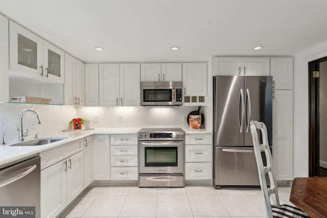 kitchen with appliances with stainless steel finishes, a sink, light countertops, white cabinets, and recessed lighting
