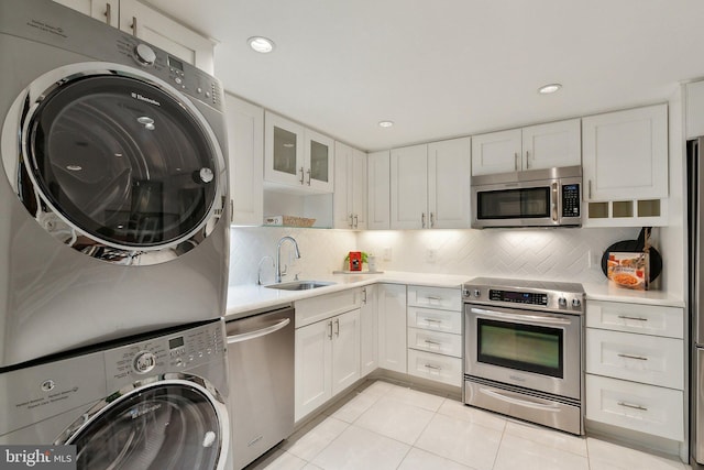 kitchen with stainless steel appliances, stacked washer and clothes dryer, white cabinets, light countertops, and recessed lighting