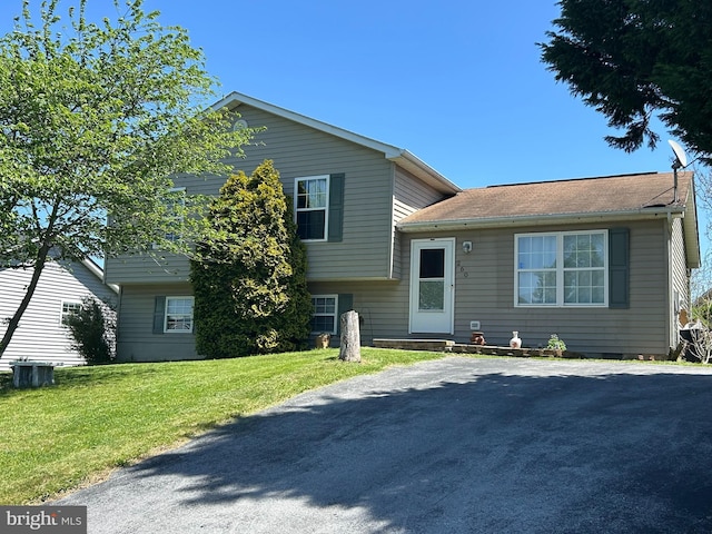 tri-level home featuring central AC and a front yard