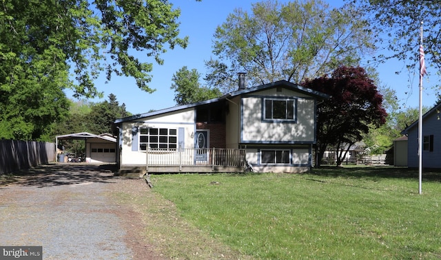 tri-level home featuring a detached garage, a front yard, dirt driveway, and fence
