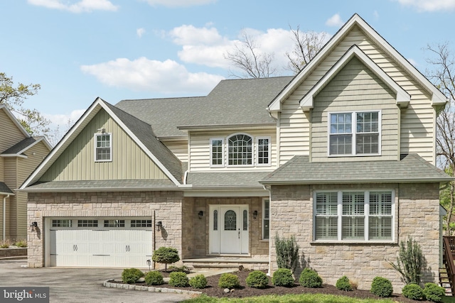 craftsman house with board and batten siding, a shingled roof, driveway, and stone siding