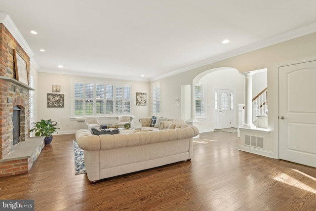 living area with arched walkways, a wealth of natural light, crown molding, and dark wood-type flooring