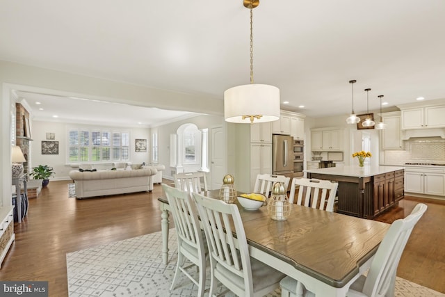 dining room featuring dark wood finished floors, recessed lighting, and arched walkways