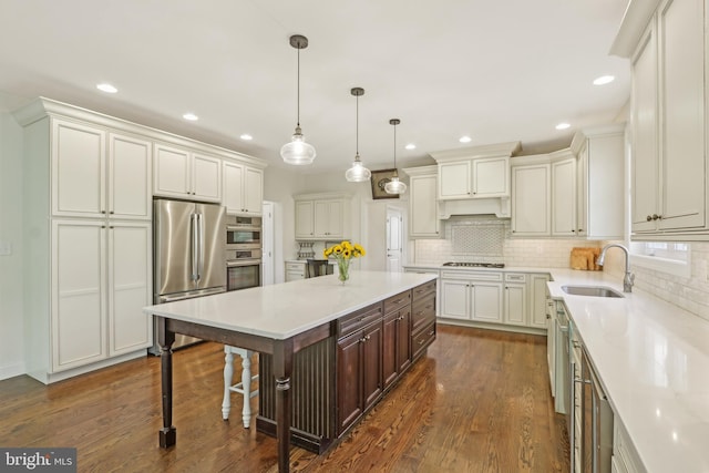 kitchen with a sink, stainless steel appliances, tasteful backsplash, a center island, and light countertops