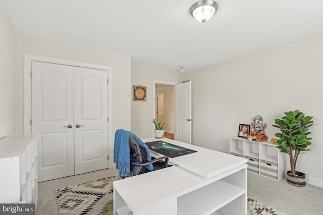 office area featuring baseboards and light carpet