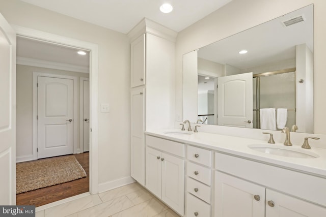 bathroom with visible vents, a shower stall, double vanity, and a sink
