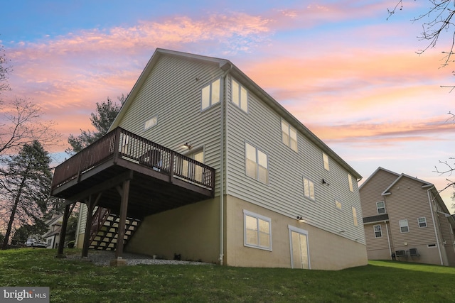 rear view of house with a wooden deck, a yard, and stairway